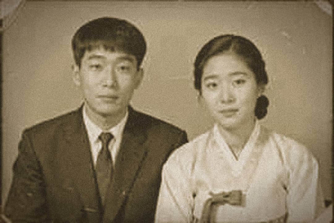 An old, faded, low-quality black-and-white photo of a couple